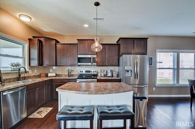 kitchen with appliances with stainless steel finishes, dark brown cabinetry, sink, pendant lighting, and dark hardwood / wood-style floors