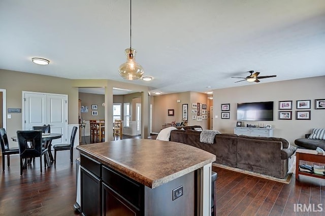 kitchen featuring ceiling fan, a center island, dark hardwood / wood-style floors, and decorative light fixtures