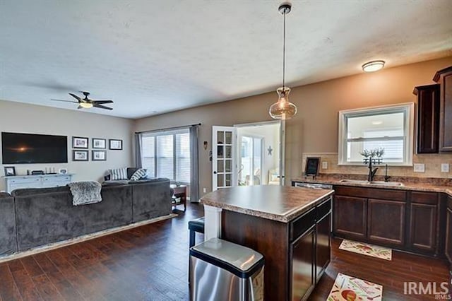 kitchen featuring decorative light fixtures, a center island, dark brown cabinetry, and sink