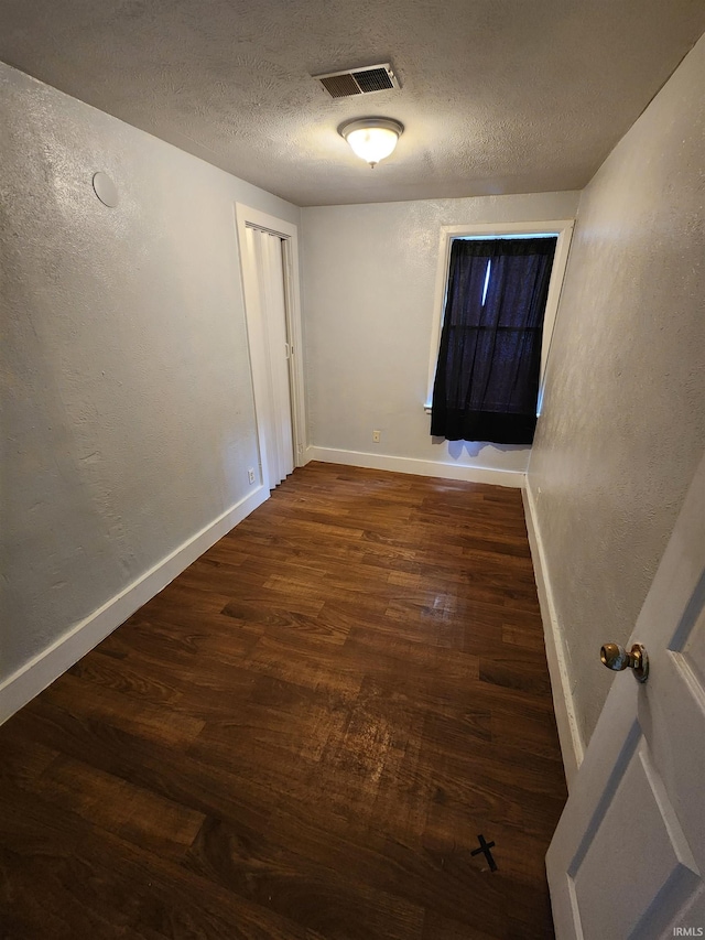 hallway with dark wood-type flooring and a textured ceiling