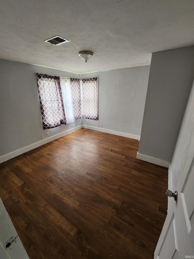 spare room featuring dark hardwood / wood-style floors and a textured ceiling