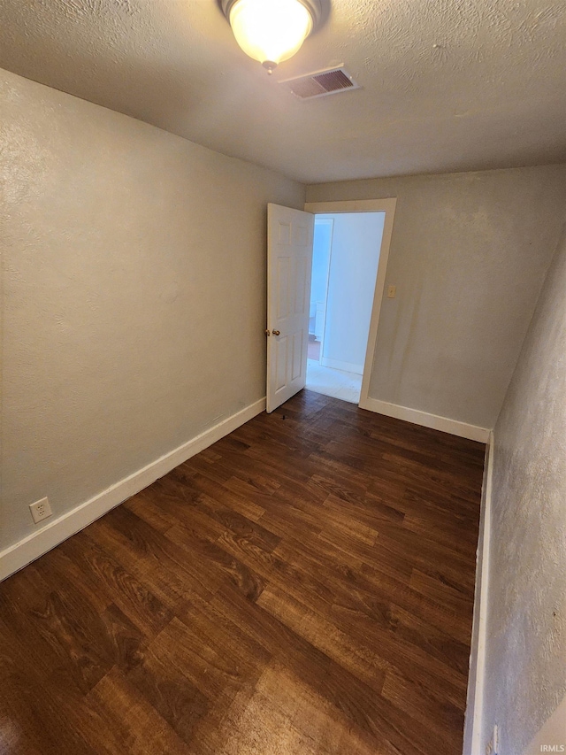 empty room with a textured ceiling and dark wood-type flooring