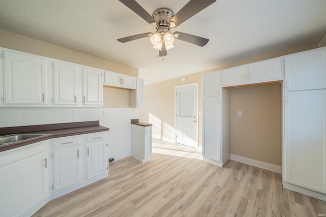 kitchen with white cabinetry, ceiling fan, sink, light hardwood / wood-style flooring, and a textured ceiling