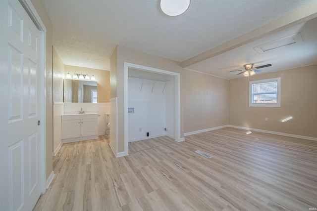 unfurnished bedroom with sink, ceiling fan, a textured ceiling, connected bathroom, and light hardwood / wood-style floors