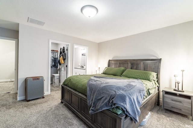 carpeted bedroom with a closet, a spacious closet, and ensuite bath