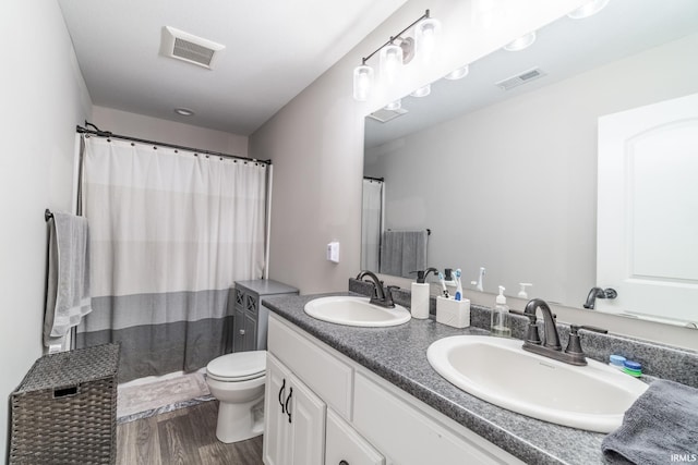 bathroom with wood-type flooring, vanity, toilet, and curtained shower