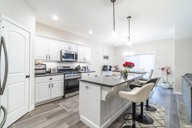 kitchen featuring a breakfast bar, white cabinets, sink, hanging light fixtures, and appliances with stainless steel finishes