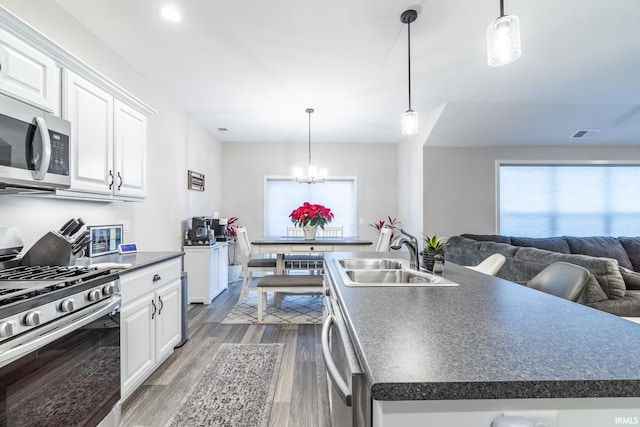 kitchen featuring sink, stainless steel appliances, white cabinetry, and an island with sink