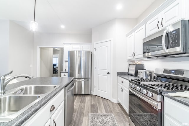 kitchen with stainless steel appliances, sink, light hardwood / wood-style flooring, white cabinetry, and hanging light fixtures