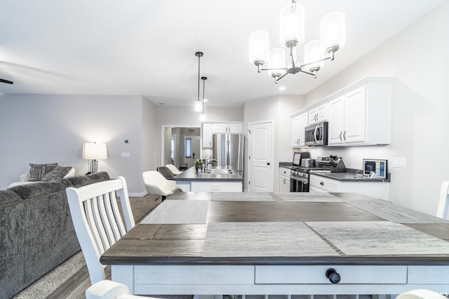 kitchen featuring an inviting chandelier, white cabinets, sink, hanging light fixtures, and stainless steel appliances