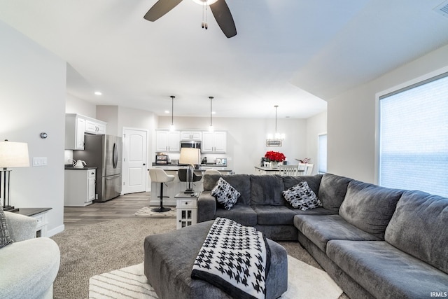 living room featuring ceiling fan with notable chandelier and dark hardwood / wood-style flooring