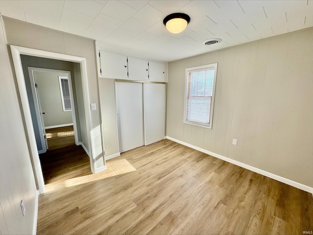 unfurnished bedroom with light hardwood / wood-style flooring and a closet