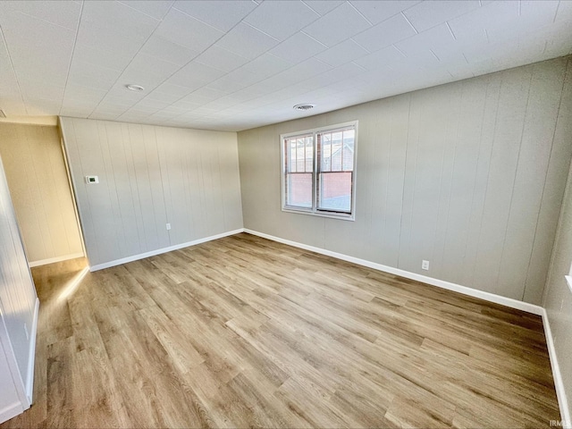 empty room featuring light hardwood / wood-style flooring and wooden walls