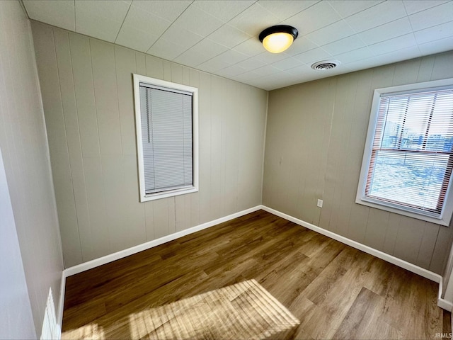 empty room featuring hardwood / wood-style floors and wood walls