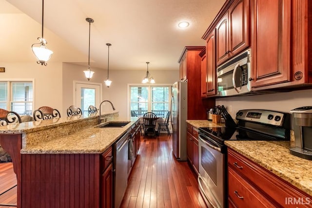 kitchen featuring sink, stainless steel appliances, an island with sink, pendant lighting, and a breakfast bar