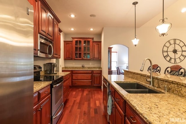 kitchen with light stone countertops, stainless steel appliances, sink, decorative light fixtures, and dark hardwood / wood-style floors