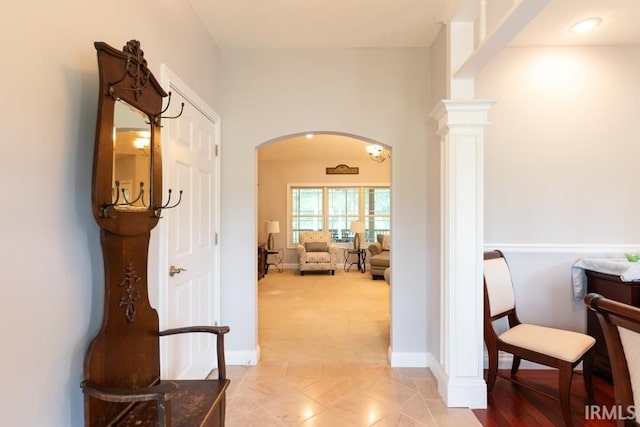 hallway featuring light colored carpet and ornate columns