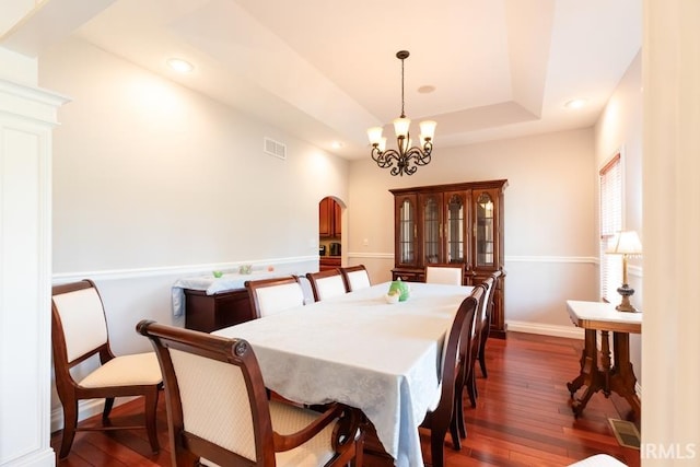 dining room with a notable chandelier, dark hardwood / wood-style flooring, and a tray ceiling