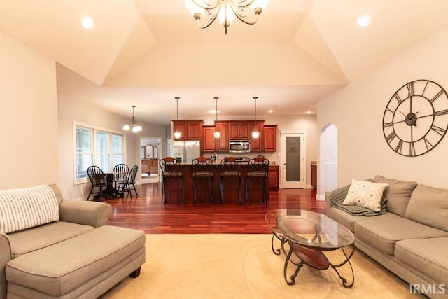 living room featuring a chandelier, vaulted ceiling, and dark wood-type flooring