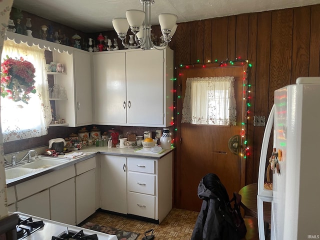 kitchen featuring sink, white cabinets, white fridge, and a notable chandelier