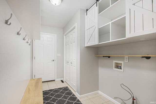 laundry area featuring light tile patterned flooring, a barn door, and hookup for a washing machine