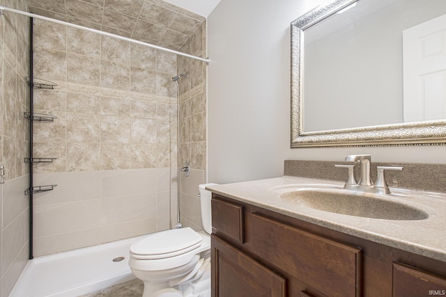 bathroom featuring a tile shower, vanity, and toilet