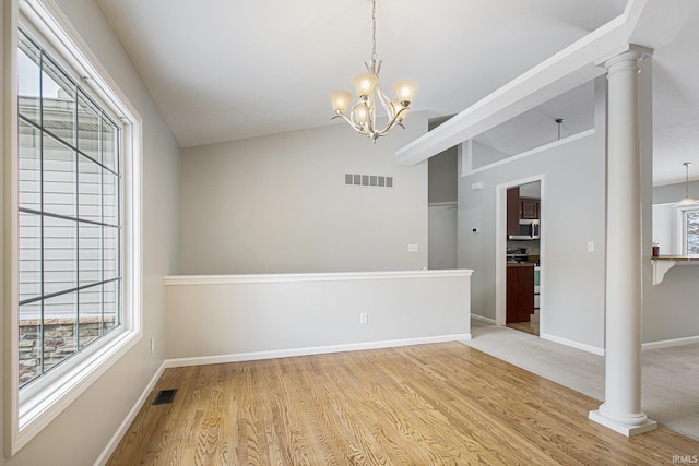 empty room featuring wood-type flooring, vaulted ceiling, and an inviting chandelier