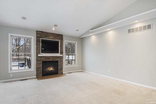 unfurnished living room with a stone fireplace, light colored carpet, and vaulted ceiling