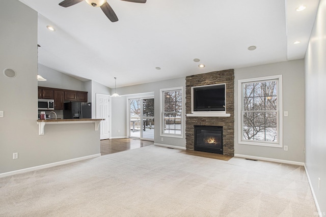 unfurnished living room with light carpet, a fireplace, and a healthy amount of sunlight