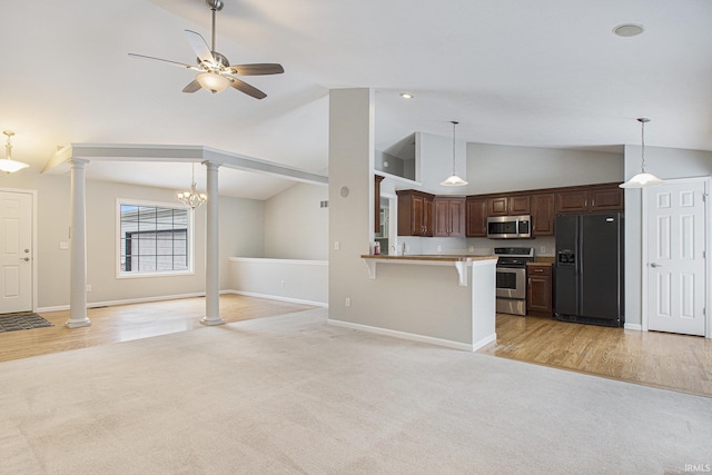 kitchen featuring a breakfast bar, ceiling fan with notable chandelier, vaulted ceiling, kitchen peninsula, and stainless steel appliances