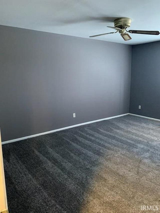 spare room with dark carpet and ceiling fan