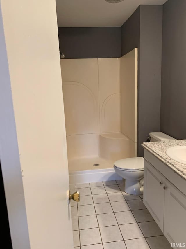 bathroom with tile patterned flooring, vanity, toilet, and walk in shower