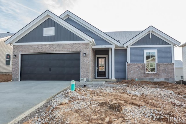 craftsman house featuring concrete driveway, an attached garage, brick siding, and board and batten siding