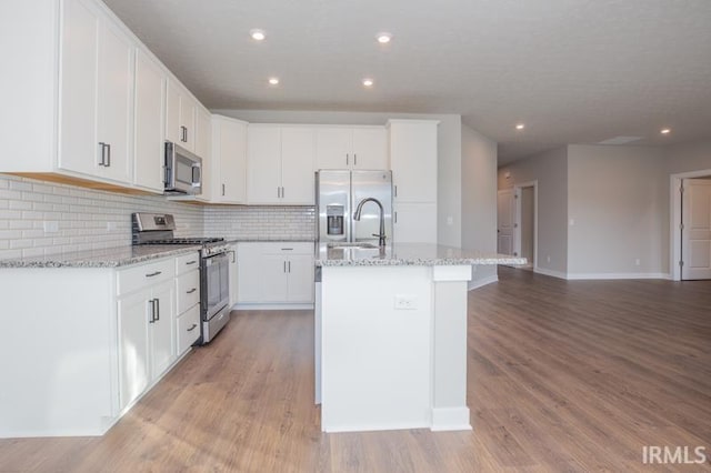 kitchen featuring a center island with sink, white cabinets, light hardwood / wood-style flooring, and appliances with stainless steel finishes