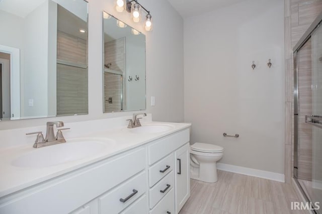 bathroom with a shower with door, vanity, and toilet