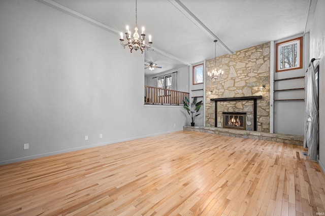 unfurnished living room with ceiling fan with notable chandelier, light hardwood / wood-style floors, a stone fireplace, and ornamental molding