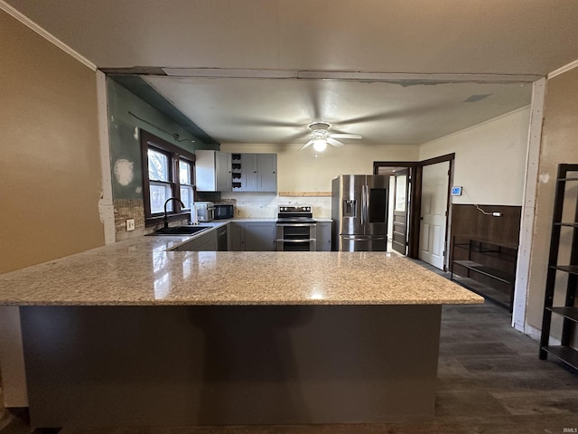 kitchen with kitchen peninsula, light stone counters, sink, and stainless steel appliances