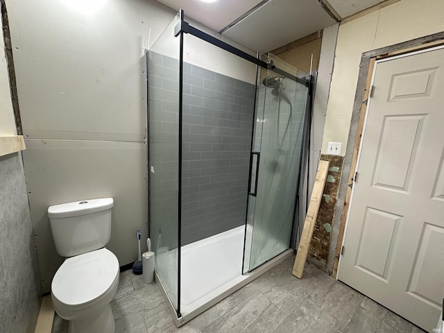 bathroom with toilet and a shower with shower door