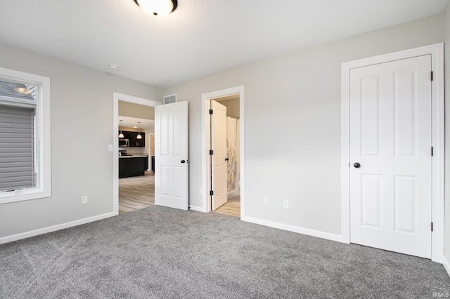 unfurnished bedroom with light colored carpet and connected bathroom