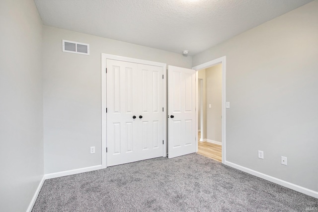 unfurnished bedroom featuring a closet, carpet, and a textured ceiling