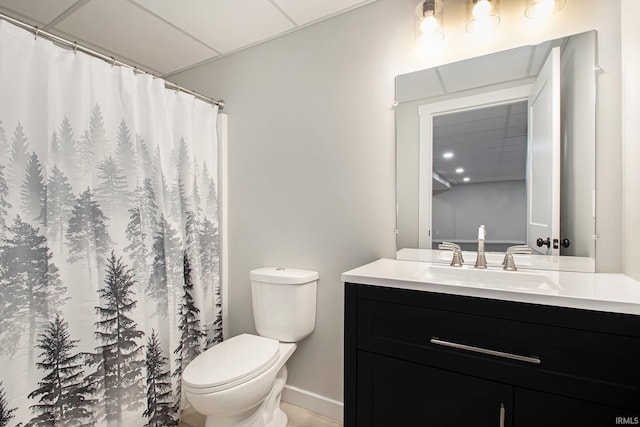 bathroom with a paneled ceiling, vanity, and toilet