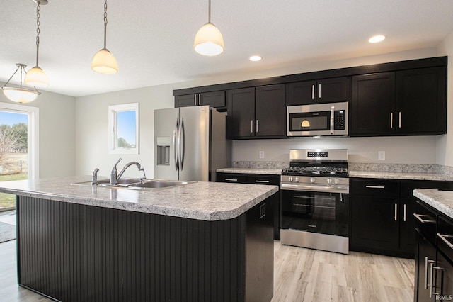 kitchen featuring pendant lighting, stainless steel appliances, a center island with sink, and sink