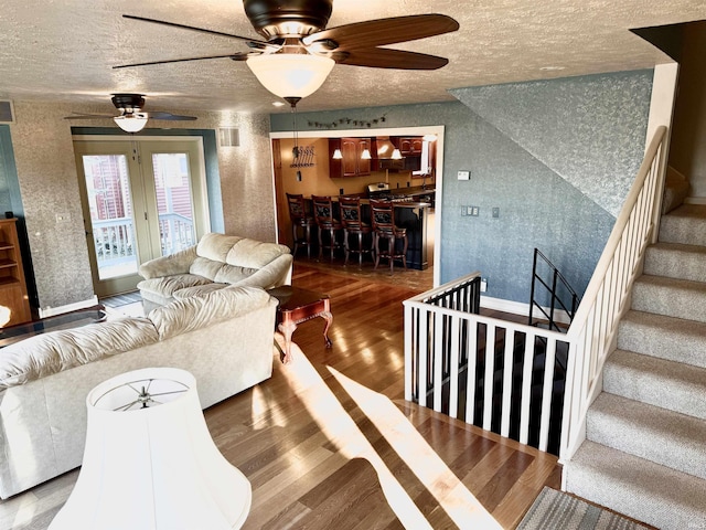 living room featuring hardwood / wood-style floors, a textured ceiling, and ceiling fan