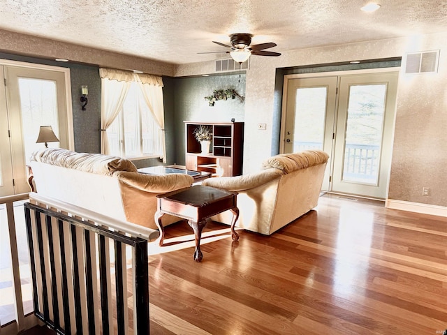 living room with ceiling fan, wood-type flooring, and a textured ceiling