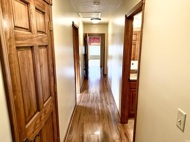 hall featuring a textured ceiling and light hardwood / wood-style flooring