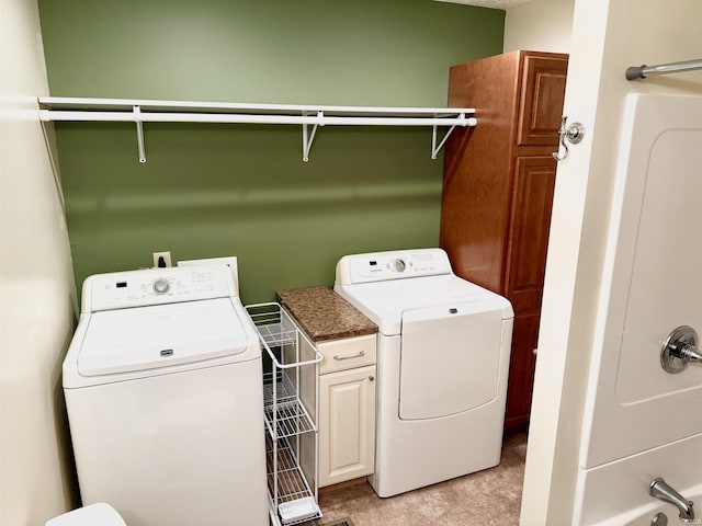 clothes washing area featuring cabinets and washing machine and clothes dryer