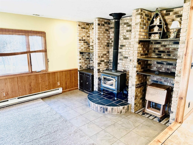 unfurnished living room featuring light tile patterned floors, a baseboard radiator, a wood stove, and wood walls