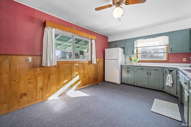 kitchen with ceiling fan, white refrigerator, and wooden walls