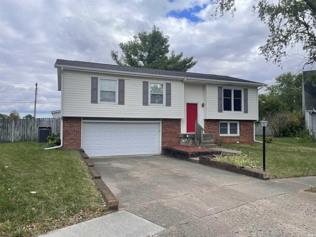 bi-level home featuring a garage, central air condition unit, and a front lawn