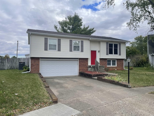 bi-level home featuring a garage, central air condition unit, and a front lawn